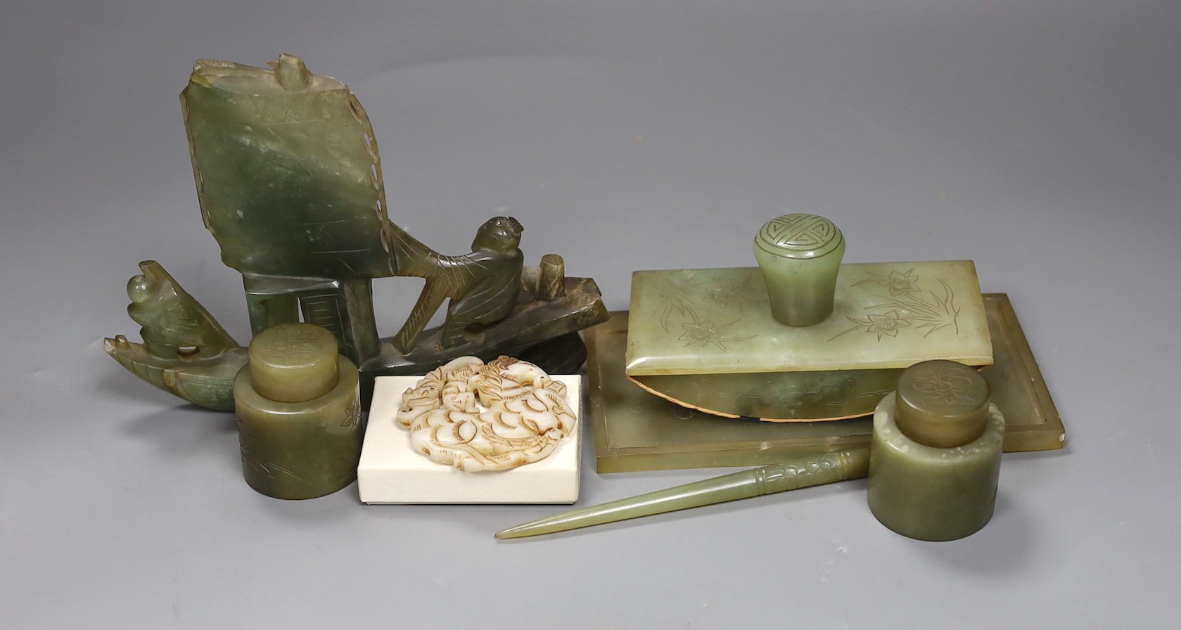 A Chinese bowenite jade desk set (7) and a plaque, model of junk 16cms high